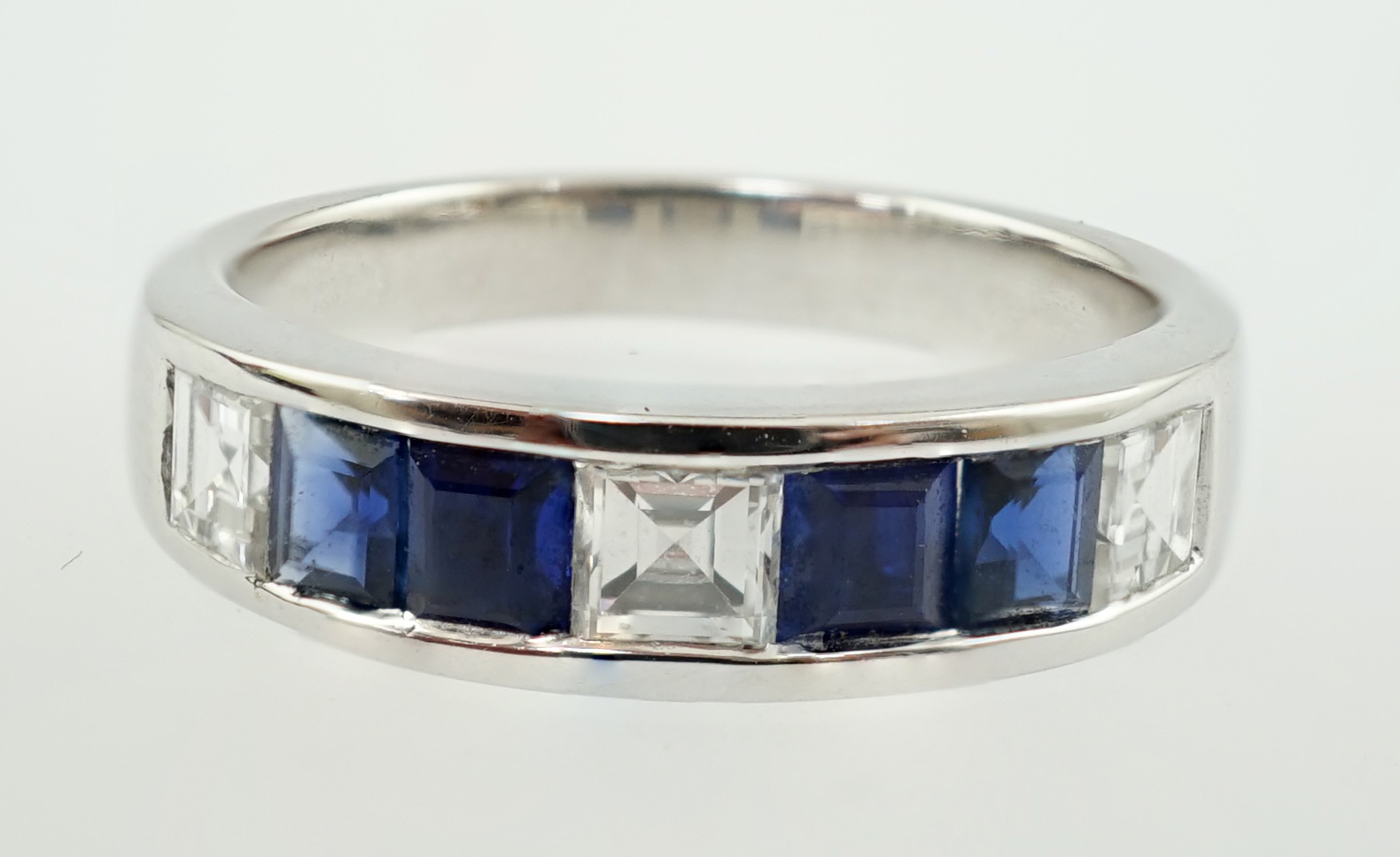 A modern 14k white gold, three stone diamond and four stone sapphire half hoop ring